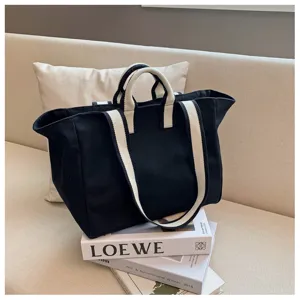Detailed view of black canvas tote bag with white webbing straps, minimalist daily style.