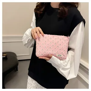 Close-up detail of a pink distressed linen cosmetic bag held by a model, perfect for travel storage.