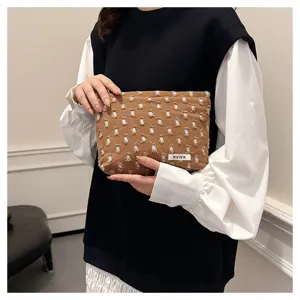 Portable brown linen cosmetic bag with frayed design, perfect for travel storage and daily use.