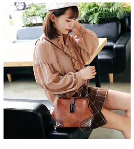 Brown vintage women leather shoulder bag with lock and metal studs detail closeup view