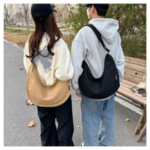 Vue de détail en extérieur montrant un sac bandoulière en toile grande capacité porté.