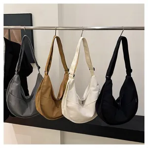 Vue détaillée de sacs cabas en toile bandoulière en quatre couleurs sur une tringle.