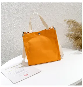 Canvas tote bag with yellow body and white handles, casual shoulder bag for daily use.