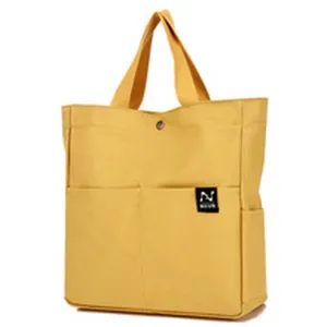 Yellow canvas tote bag detail, multi-pocket design, durable fabric, casual daily handbag.