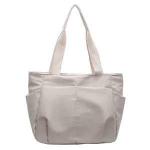 Detail view of the elegant beige shoulder tote bag featuring multiple convenient exterior pockets.