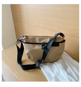 Detail view of stylish khaki nylon crossbody bag featuring black strap and minimalist design.