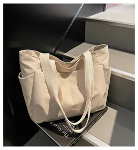 Minimalist beige canvas tote bag for women, featuring spacious interior and convenient side pockets.