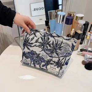 Vue détail d'une trousse de maquillage en tissu stylée avec imprimé palmiers bleus et design portable.