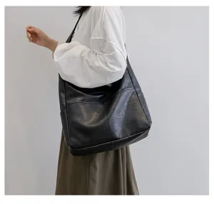 Detail shot of black PU leather shoulder tote bag, showing neat stitching and soft texture.