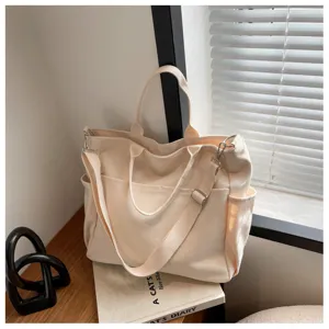 Detailed view of the multi-pocket canvas tote bag in beige with adjustable shoulder strap.