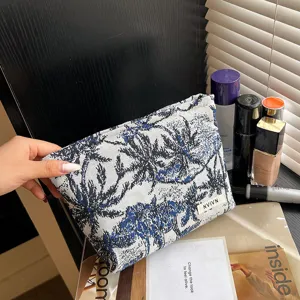 Gros plan sur la trousse de maquillage tissée à motif botanique bleu et blanc en détail.