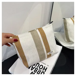 Detailed view of the striped woven cosmetic pouch, showing texture and handle grip.