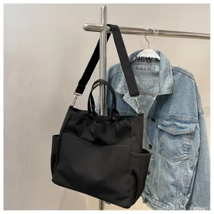 Canvas tote bag with multi pockets and shoulder strap detail shot on clothing rack display.