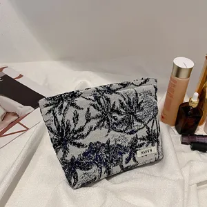 Gros plan sur la pochette de maquillage imprimé palmier avec sa texture en tissu et étiquette.