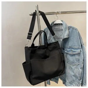 Detailed view of a black canvas multi-pocket tote bag hanging on a metal display rack.