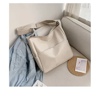 Detail view of the beige PU leather shoulder tote bag, showing stitching and front pocket.