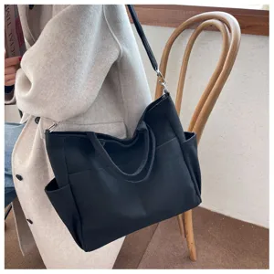 Black canvas tote bag detail view, multi-pocket design showing daily storage capacity and durable strap.