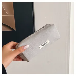 Detail view of a minimalist light grey canvas pencil pouch with zipper and custom label tag.