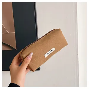 Detail shot of a simple brown canvas pencil case held by hand, showing textured fabric tag.