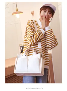 Detailed lifestyle shot of a casual white canvas shoulder tote bag featuring front pockets
