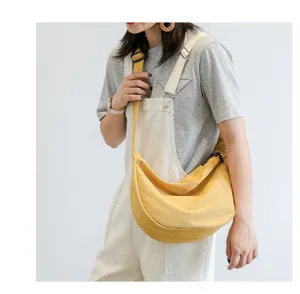 Gros plan détaillé du sac bandoulière en nylon jaune porté par le modèle, style décontracté.