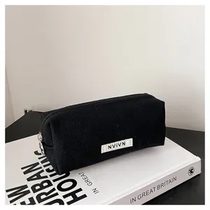 Detailed view of a minimalist black canvas pencil case resting on a book, showing texture.