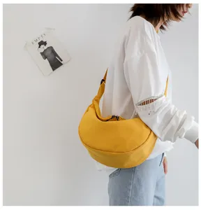 Detail view of a yellow nylon crossbody dumpling bag, showing its soft shape and casual style.