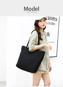 Vue détaillée du sac cabas fourre-tout noir en toile porté par le mannequin en scène.