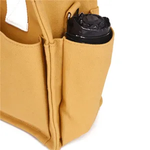 Yellow canvas tote bag detail shot showing external side pocket with folded umbrella inside.