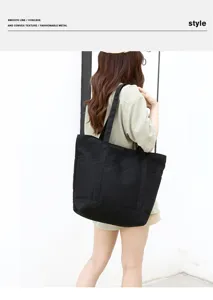 Gros plan détaillé d'un sac cabas en toile noire porté par un mannequin dans une scène quotidienne.