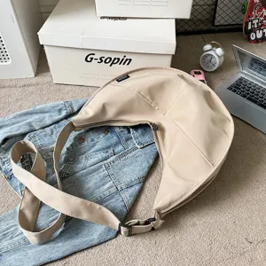 Detailed shot of solid color crescent crossbody dumpling bag with wide strap and zipper.