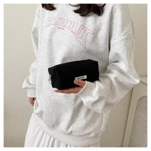 Detailed view of black canvas pencil pouch held by hand, showing smooth metal zipper.