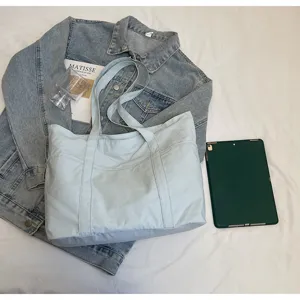 Casual solid color canvas tote bag with multiple pockets for daily commuting and travel.