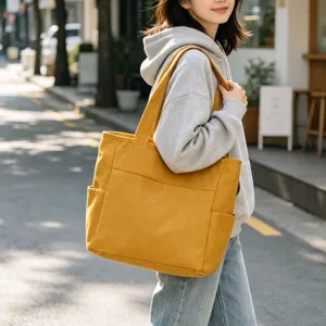 Detail view of a yellow canvas tote bag in daily street scene, large daily capacity.