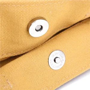 Close-up detail of canvas bag metal magnetic snap button closure, fine hardware craftsmanship.