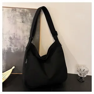 Black canvas tote bag with adjustable strap and front pocket, perfect for daily casual use.