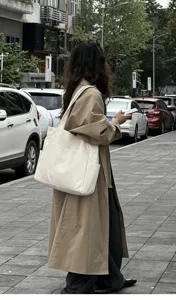 Outdoor street detail view showcasing a large white canvas tote bag worn by a model.