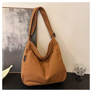 Brown canvas shoulder bag detail showcasing durable fabric texture, side woven label and strap.