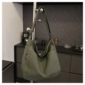 Detailed view of the olive green canvas shoulder bag showing adjustable strap and side tag.
