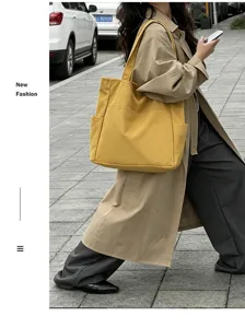 Street style detail shot of large capacity yellow canvas tote shoulder bag for daily commute.