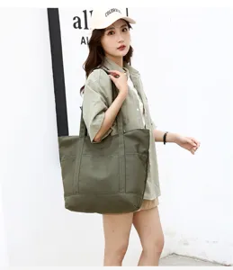 Vue détaillée du sac cabas en toile vert foncé avec poche avant et double poignée.