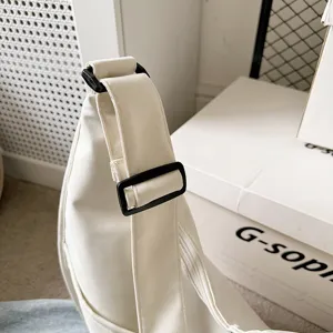 White dumpling bag detail close-up showcasing adjustable black buckle strap and clean fabric.