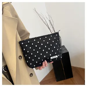 Black linen textured makeup bag with white dotted details, portable travel storage pouch detail.