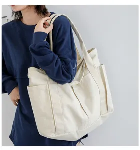 Canvas tote bag detail view showing large capacity, side pockets, and durable shoulder straps.