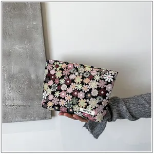 Floral cosmetic bag detail, woven fabric pouch with colorful flower pattern and small tag.