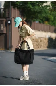 Close-up of a stylish black canvas tote bag featuring multiple pockets and durable twin handles.