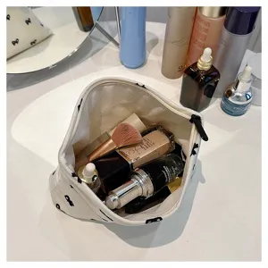 Detailed shot of a canvas cosmetic bag with cute bow prints, open view showing makeup storage.