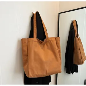 Brown canvas tote bag detail view, featuring durable shoulder straps and a practical side pocket.