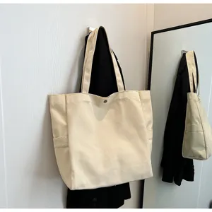 Detailed view of casual canvas tote bag with side pocket hanging on wall, neutral tone.