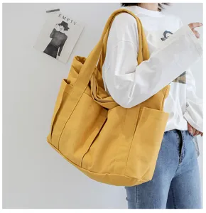 Yellow canvas tote bag detail view showing multiple exterior side pockets and shoulder strap.